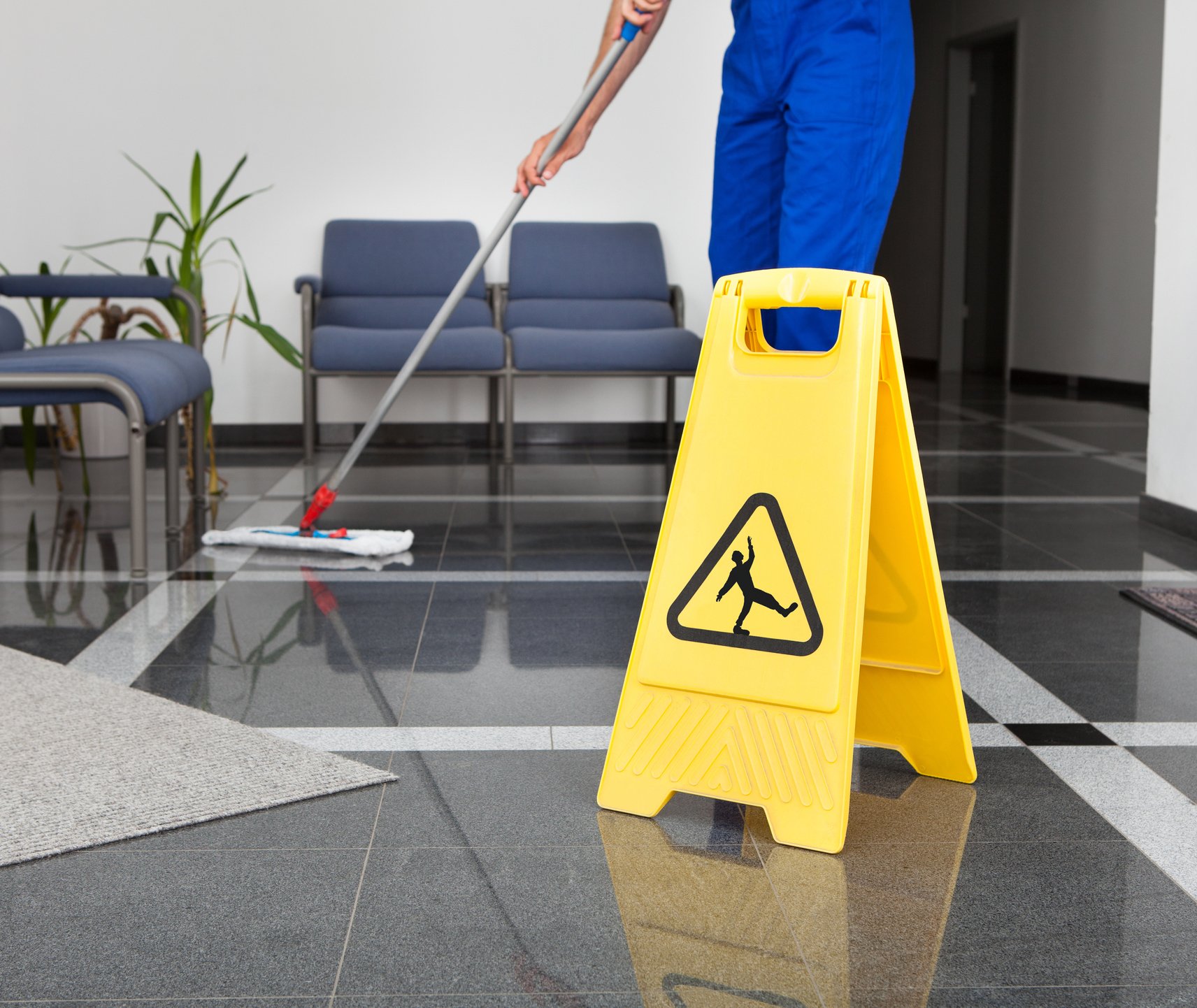 Close-up Of Janitor Cleaning The Floor With Yellow Wet Floor Sign