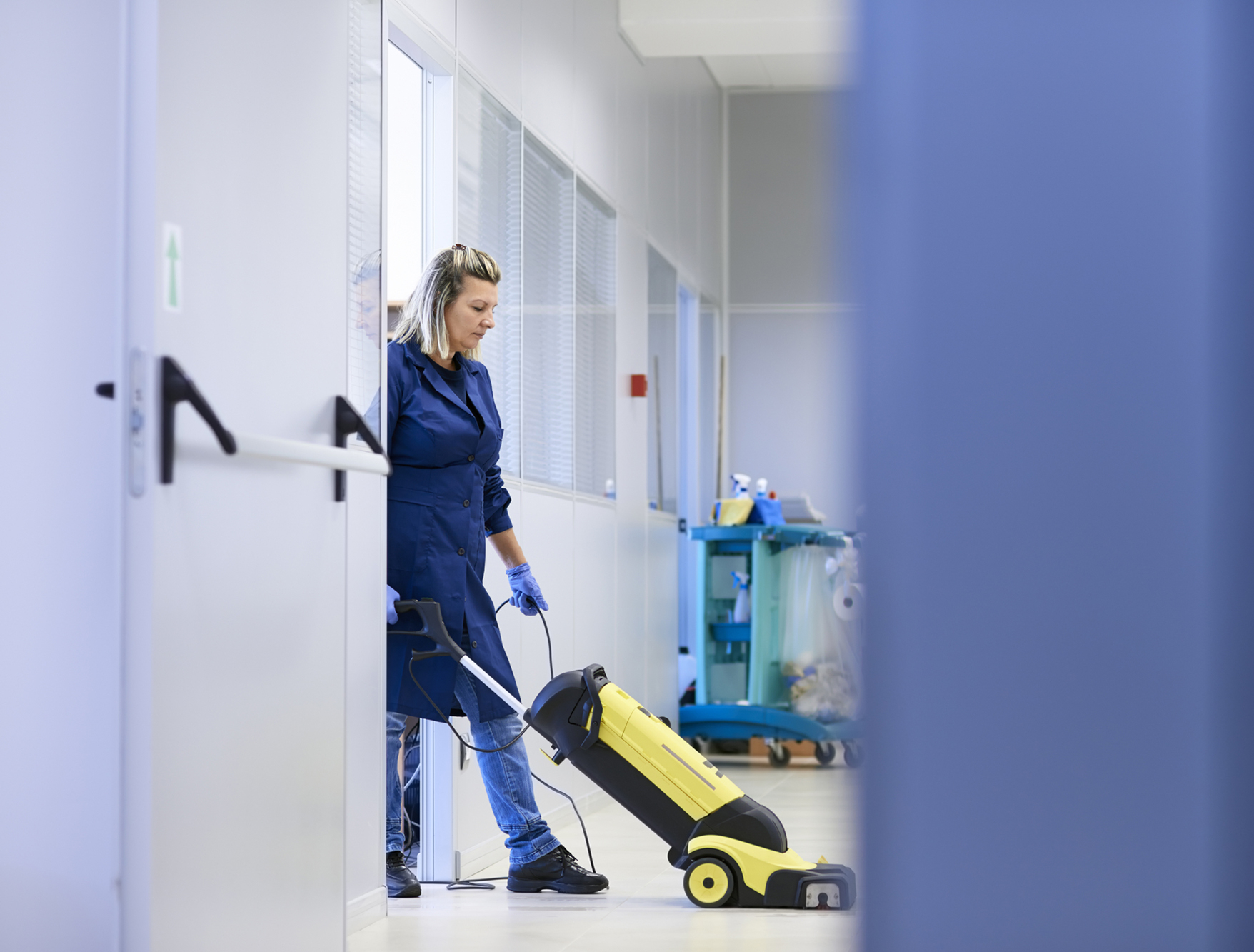 Professional Female Cleaner Vacuuming Floor In Office